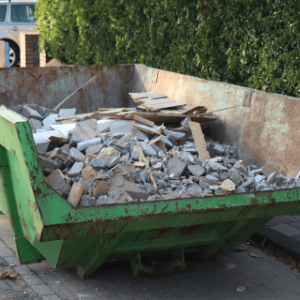 commercial dumpster rental woodstock ga - Tips for Business Owners on Dumpster Rental - a green fron-loading dumpster filled with construction debris