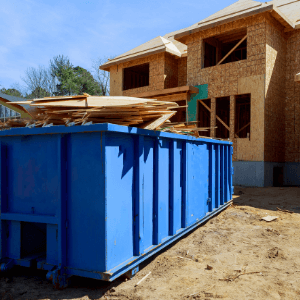 who has the cheapest dumpster rental near me - a blue dumpster being filled with construction debris from a house being built in the background